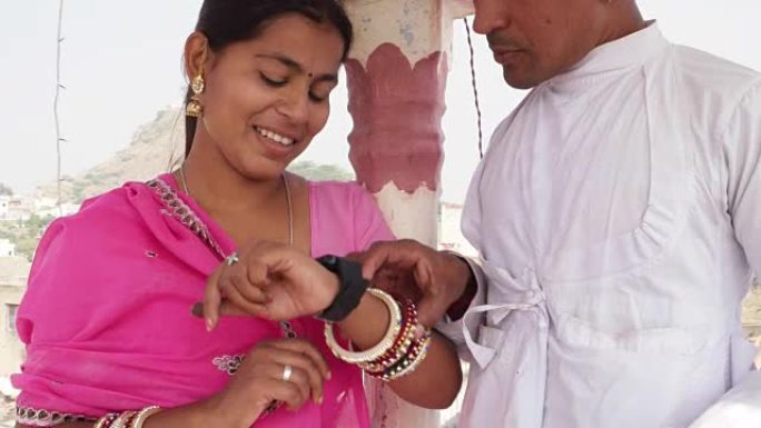 拉贾斯坦夫妇带着智能手表工作学习教学，分享穿着粉色纱丽和红色头巾在印度