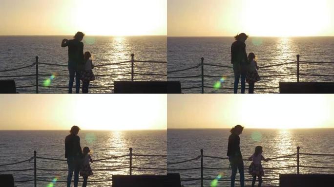 母女在海洋上观看日落的剪影