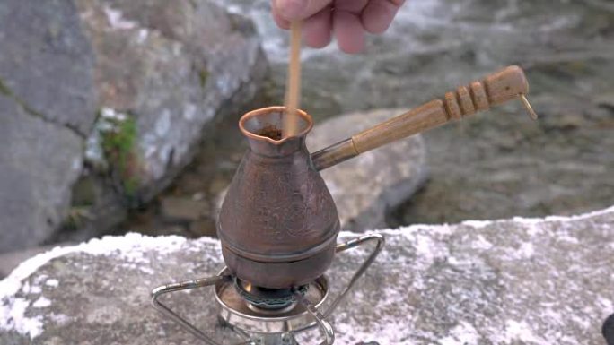 在便携式燃气燃烧器上，有一个煮咖啡的水壶。在山河附近野餐。特写