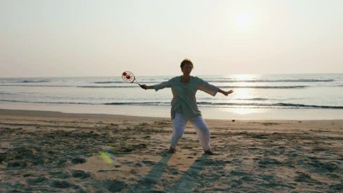 日落时在海滩上练习太极拳气球的高级女子
