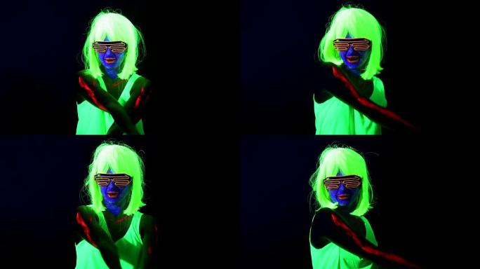 女人用紫外线的脸漆，假发，发光的衣服在镜头前跳舞。高加索女人。。
