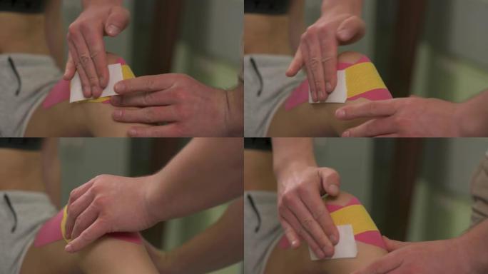 放在膝盖上的双手摩擦kinesiotape的特写镜头。如果前十字韧带受伤，治疗师会对膝关节进行运动。