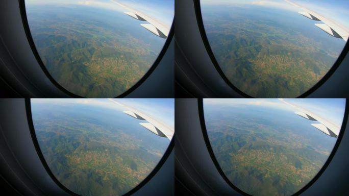 飞机上透过窗户座位看山景，飞行时有云和蓝天