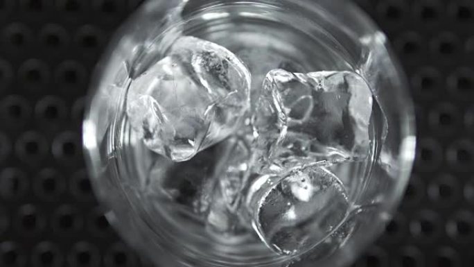 冰块落入鸡尾酒杯并滚动的宏观镜头。鸡尾酒制作。