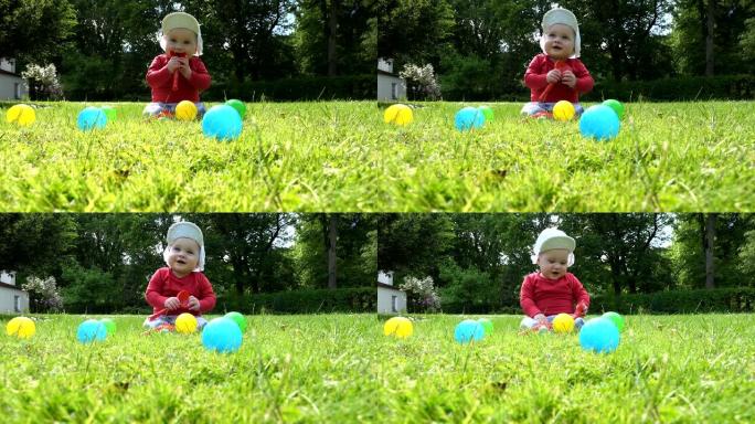 男婴坐在草地上，在五颜六色的球之间玩耍。4K