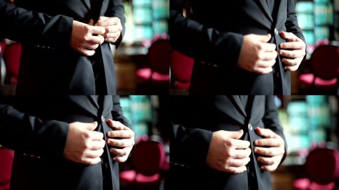 MS手持相机: 一个穿着黑色西装的男人用模糊的背景扣了夹克。