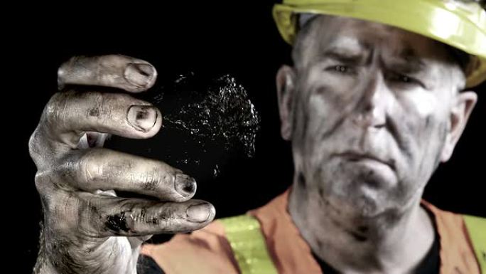 一个煤矿工人检查刚从矿井中挖出的一块煤的概念性视频。
