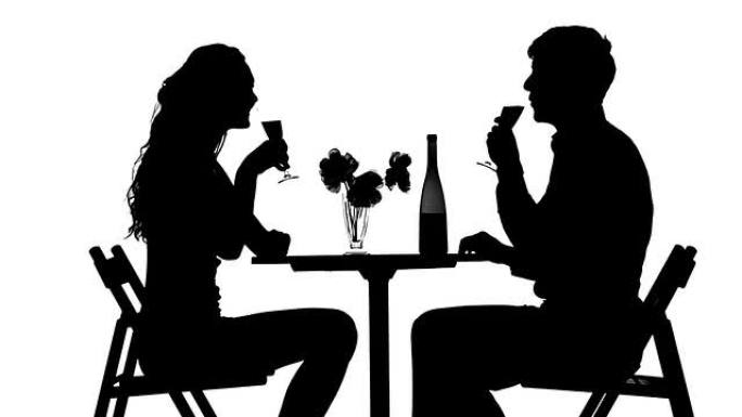 浪漫的情侣共进晚餐，碰杯。剪影