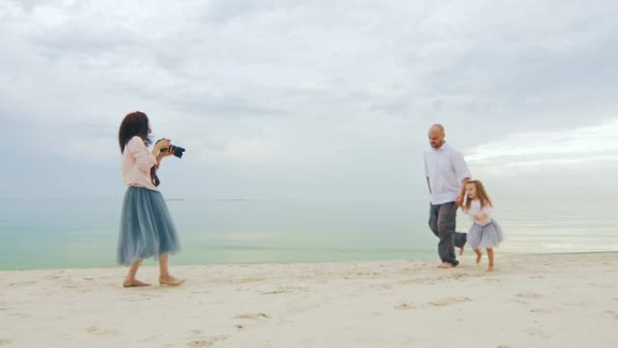全家福拍摄。妈妈在海滩上给爸爸和女儿拍照