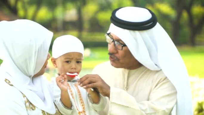 穆斯林儿子在公园吃最喜欢的糖果并与母亲分享