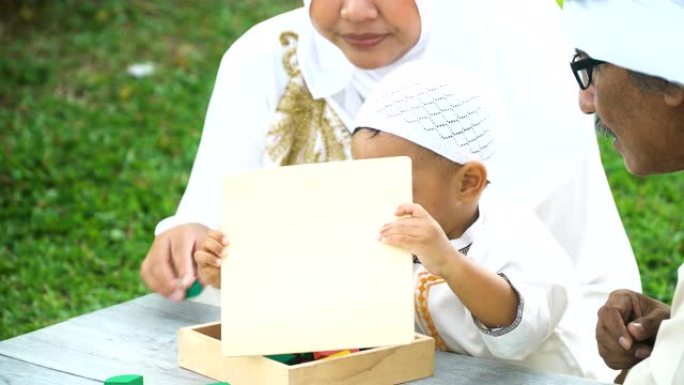 高视角: 穆斯林家庭与儿子一起在公园里学习蜡笔和木制玩具