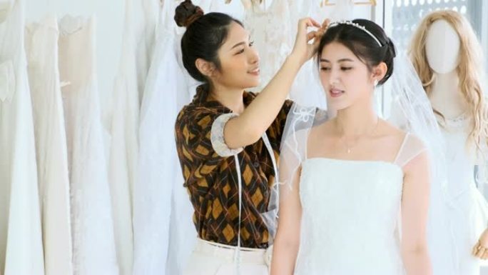 年轻的时装设计与她的顾客，尝试她的新婚纱。