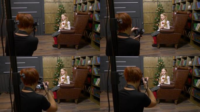 美国巴尔的摩-2018年12月25日: 少女在书柜和照相馆的圣诞树上，坐在皮革扶手椅上摆姿势。在新年