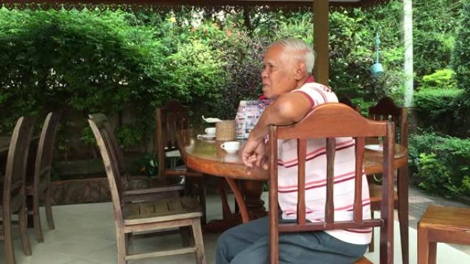 老人坐在桌子上，在喝茶的时候聊天