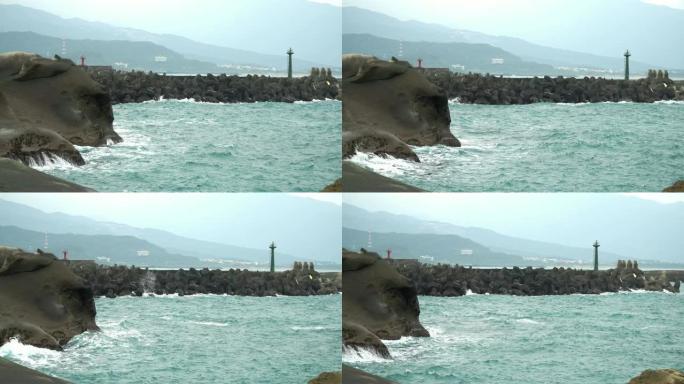 在雾天，用灯塔和海岸冲向岩石海岸的4k稳定海浪拍摄。海浪溅到石头上，溪流猛烈地流过岩石。