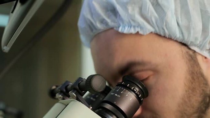 留胡子医生的眼睛在医学实验室的显微镜系统的目镜上