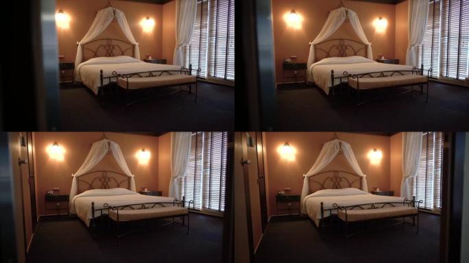 漂亮的双人床站在一个舒适的小酒店房间里。摄像机从左向右移动。
