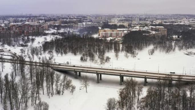 在美丽的城市或城镇下雪的冬天。夹。结冰的河流的俯视图，道路上的许多汽车，古老的建筑。大城市迷人的冬季