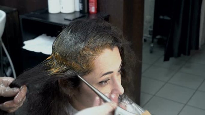 美发师-发型师在坐在沙龙美容镜子前的各个发型师上涂上油漆。头发护理。特写。从顶部看。4 k.25 f