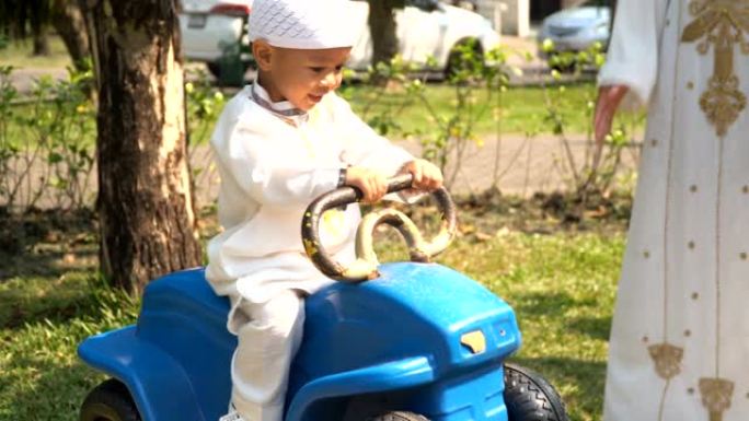 穆斯林母亲让儿子早上在公园的摇车上玩耍