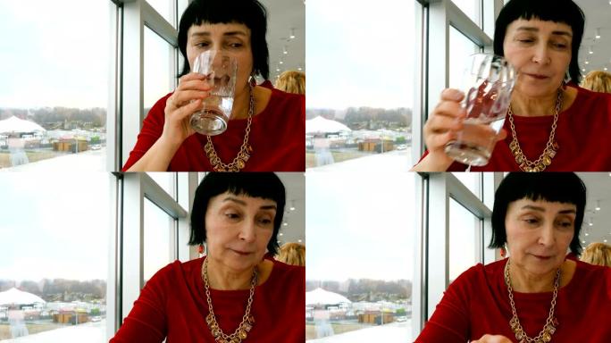 优雅的老年妇女，白人，从透明玻璃杯中喝水。
