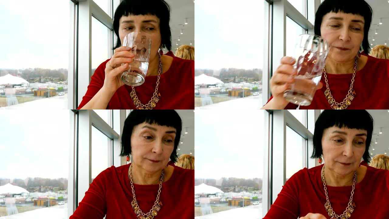 优雅的老年妇女，白人，从透明玻璃杯中喝水。