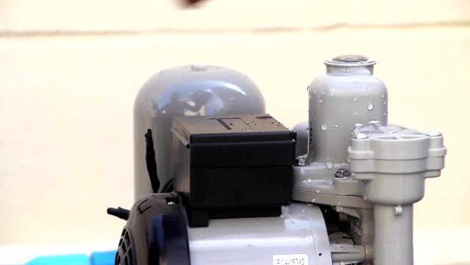 水管工将电线绑在组装用于家庭供水的水泵灌溉上，特写镜头。