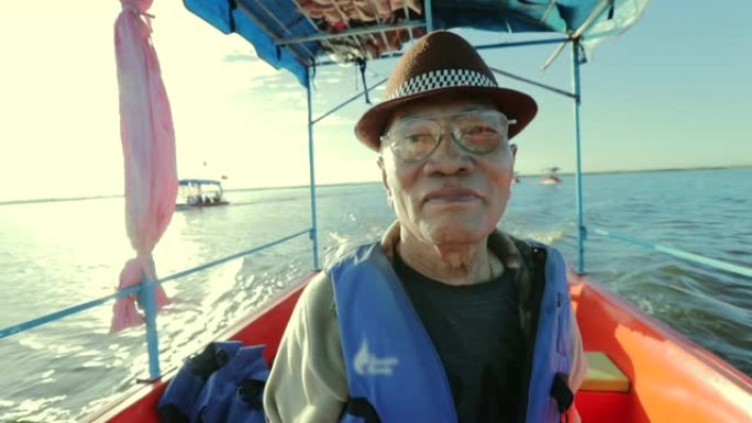 亚洲高级男性的快乐时光，在船上的湖边欣赏日出的景色，慢动作