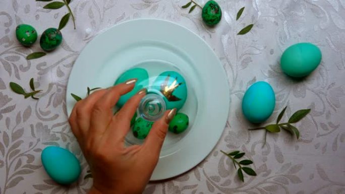 用手从装有绿色鸡蛋的盘子中取出圆顶