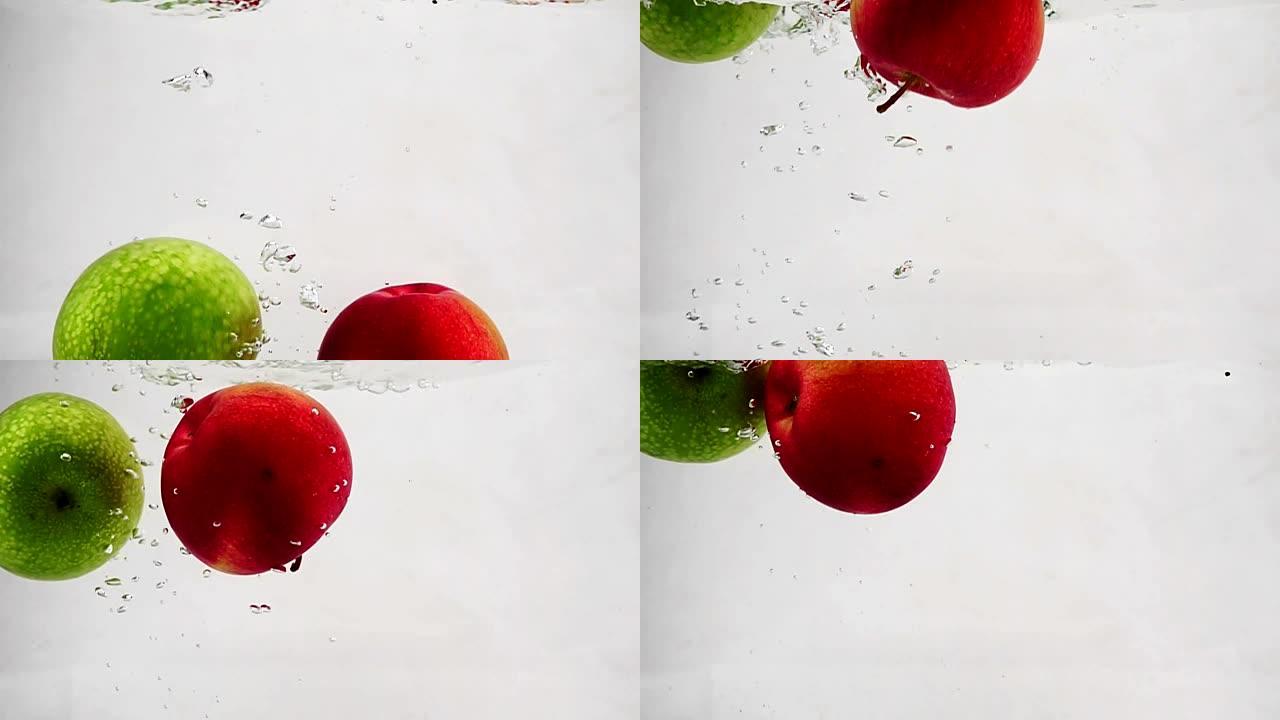 绿苹果和红苹果随气泡落入水中的慢动作视频。孤立背景上的水果。