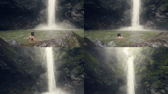 微笑的女人在热带森林的背景瀑布上沐浴在山湖中。快乐的女人在野生丛林的瀑布湖享受淡水。