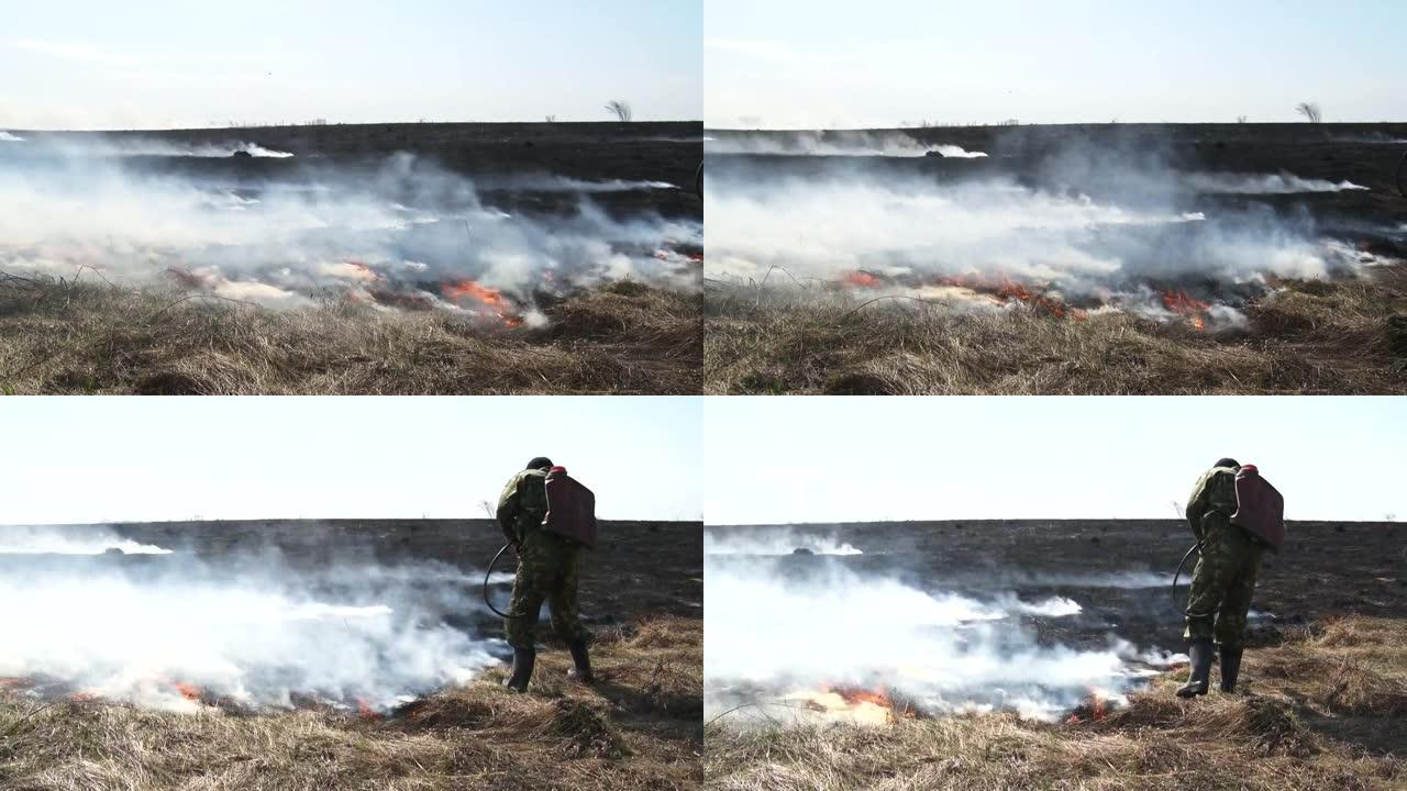 生态。燃烧的草。风中的火和烟。这个人扑灭了火焰。