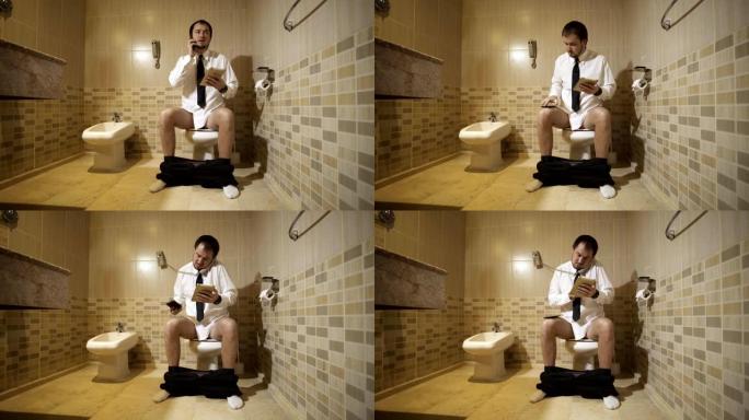 一个男人坐在豪华洗手间的马桶上，拿着电话工作。全高清