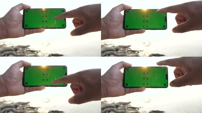 男子手持和滚动智能手机，绿屏模拟太阳背景