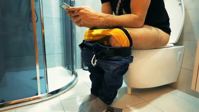 坐在马桶上的男人使用智能手机