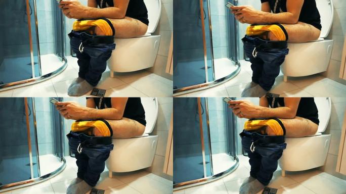 坐在马桶上的男人使用智能手机