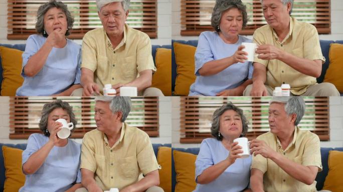 亚洲老年夫妇老人吃药，在家客厅喝水。