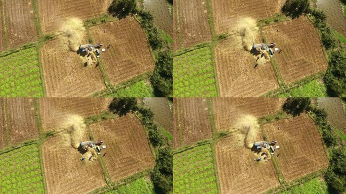 农民在田间用机器脱粒水稻的俯视
