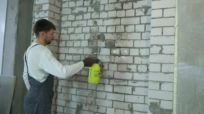 建筑工人用喷水器润湿砖墙