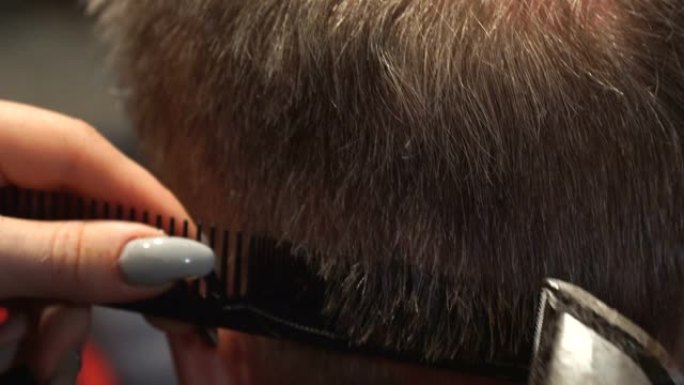 女理发师用电动理发剪男人的头发