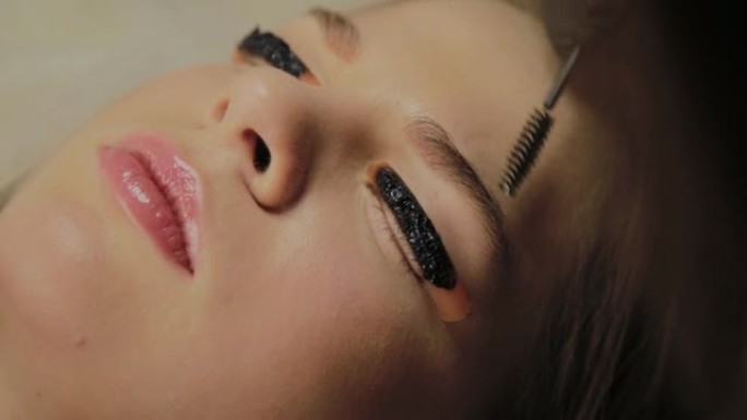 美容院里一个非常漂亮的女孩做层压睫毛。美容师在睫毛上涂上油漆