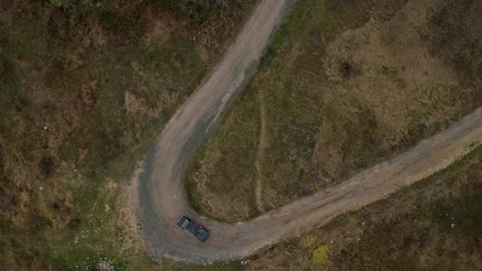 汽车在狭窄弯道上行驶的空中俯视图。旧黑色宝马在狭窄的乡村道路上的鸟瞰图