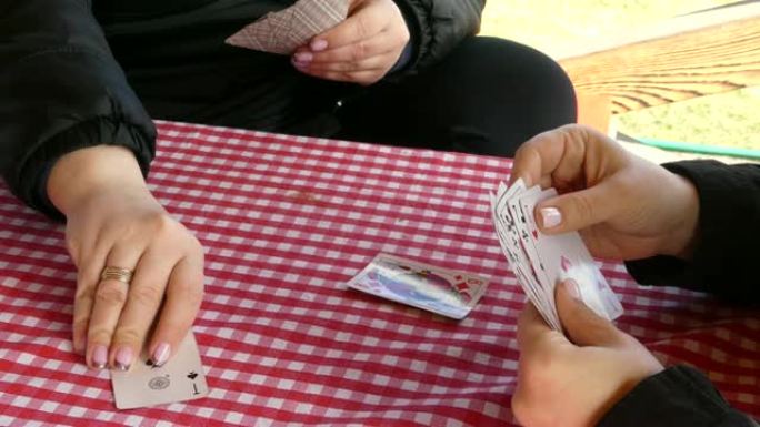 女孩在木棚里玩赌博。在桌子上玩牌。女孩们玩扑克牌。扑克。