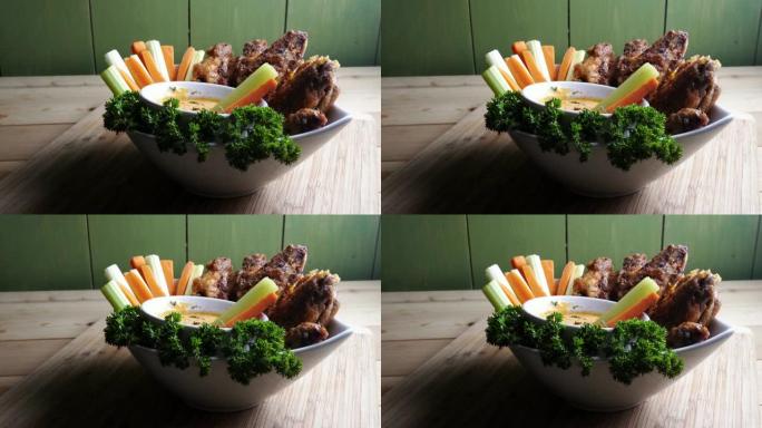 一碗健康烘烤的烤鸡翅，配以辣酱芹菜和胡萝卜条