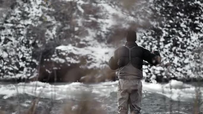 一个站在白雪皑皑的风景前的河里的男人抛弃了他的钓鱼线