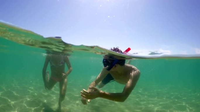 带着浮潜面具的夫妇在暑假在绿松石清水潜水时玩得开心，gopro圆顶拍摄