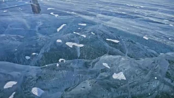 雪在冰面上飞舞。雪花在贝加尔湖的冰上飞舞。冰非常美丽，有不同寻常的独特裂缝。雪闪闪发光，发出红色光芒