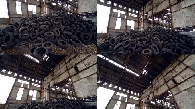 旧的灰色墙壁背景下，一堆旧的汽车轮胎在废弃的工厂内的地面上