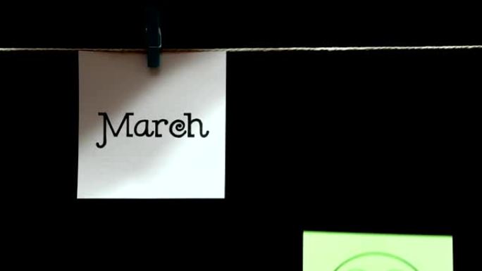 两个贴纸。情感。左边白纸上写着三月。在右边的绿色单子上，脸上表达着爱钱的表情。黑色背景。
