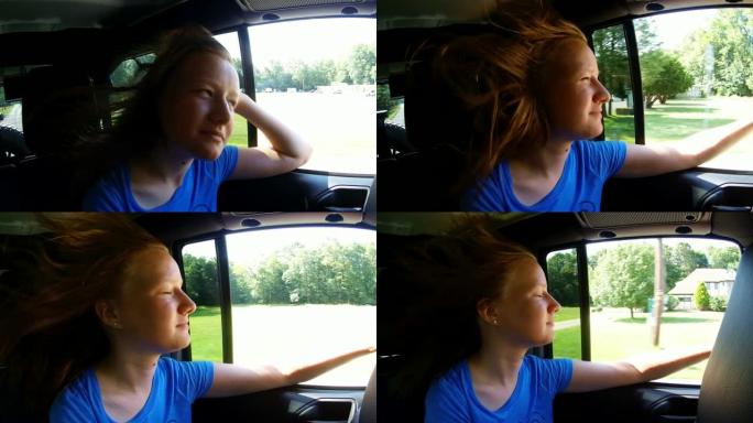 公路旅行。长发的高加索少女骑在汽车后座上，透过窗户看，玩得很开心。